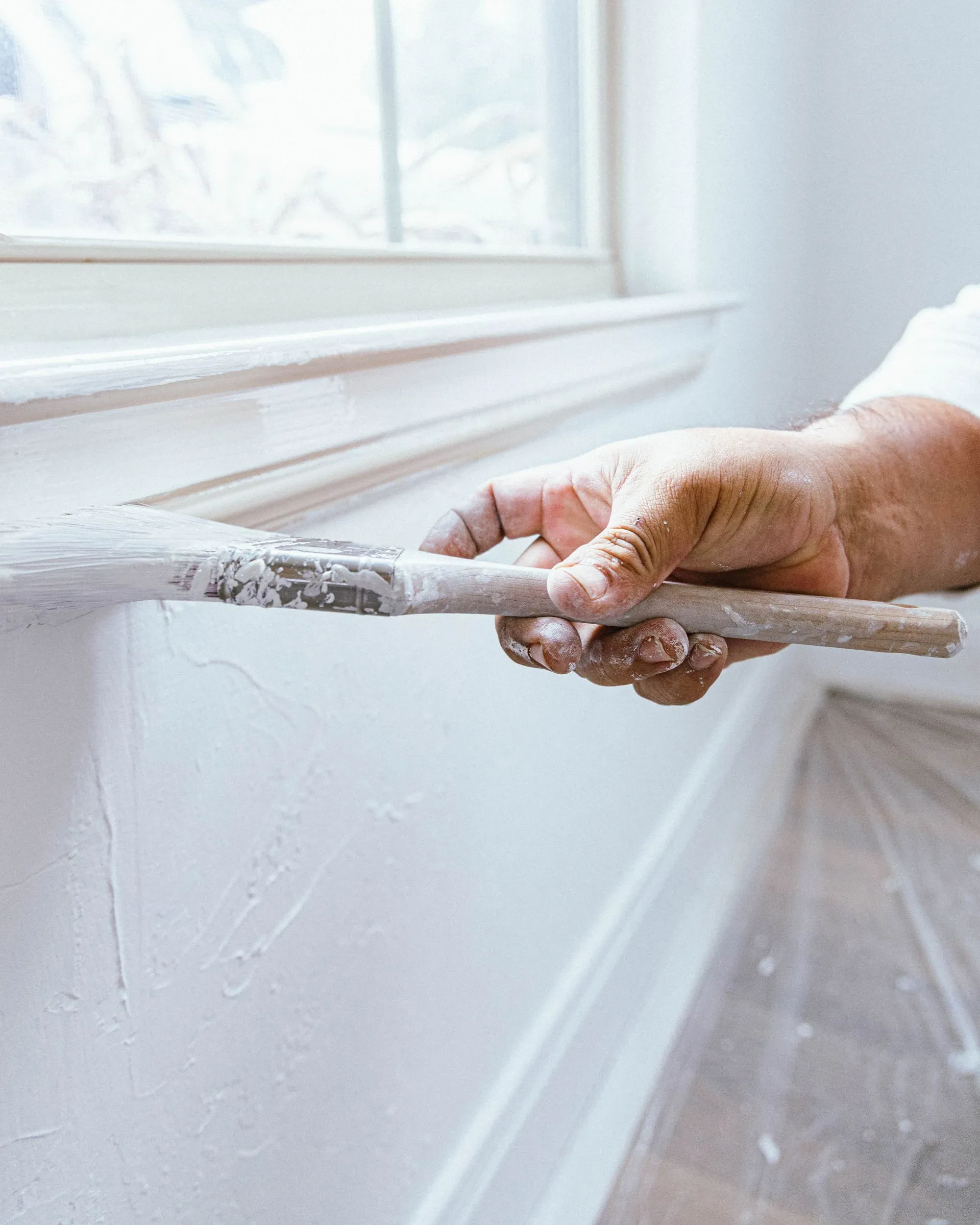 A painter applies a second coat of paint to a window apron